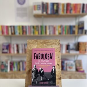 A copy of 'Fabulosa' sits on a stand in front of multiple shelves of other books.