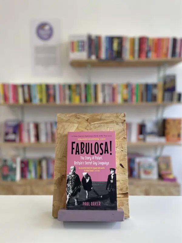 A copy of 'Fabulosa' sits on a stand in front of multiple shelves of other books.