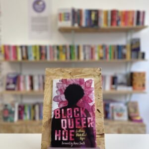 A copy o 'Black Queer Hoe' sits on a stand in front of multiple shelves of other books.