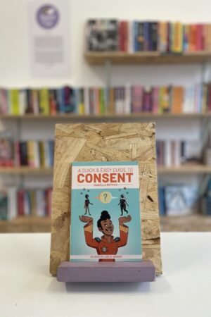 Cymraeg: Copi o 'A Quick & Easy Guide to Consent' yn sefyll ar stondin llyfrau, tu blaen silffoedd o lyfrau yn y cefndir. | English: A copy of 'A Quick & Easy Guide to Consent' sits on a stand in front of multiple shelves of other books.