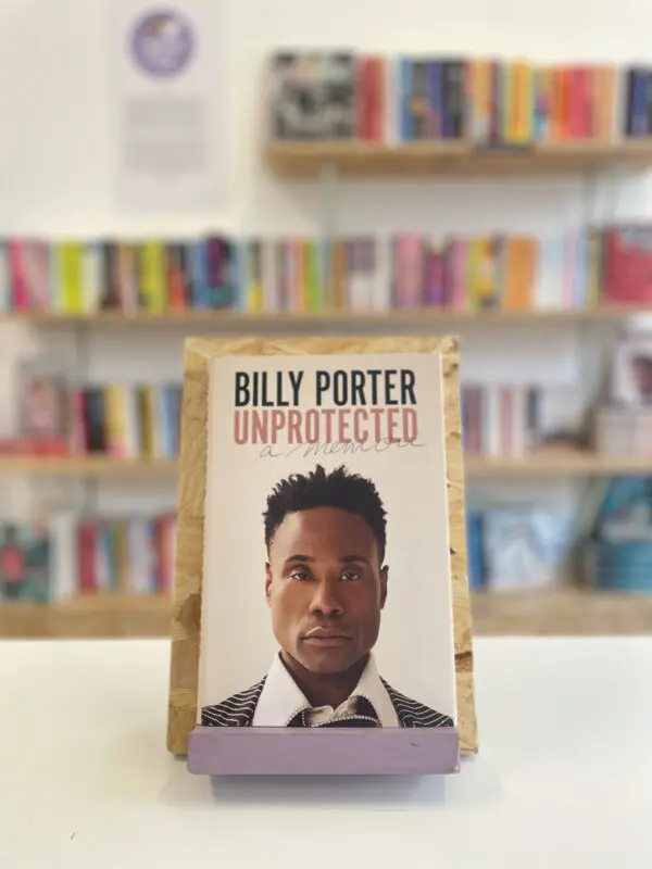 A copy of 'Unprotected' sits on a stand in front of multiple shelves of other books.