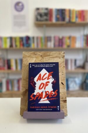 A copy of 'Ace of Spades' sits on a stand in front of multiple shelves of other books.