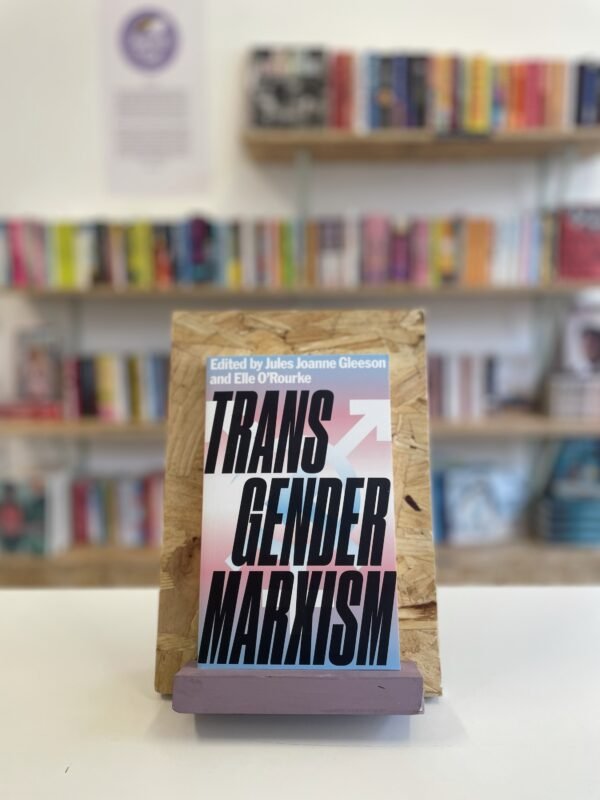 Cymraeg: Copi o 'Transgender Marxism' yn sefyll ar stondin llyfrau, tu blaen silffoedd o lyfrau yn y cefndir. English: A copy of 'Transgender Marxism' sits on a stand in front of multiple shelves of other books.