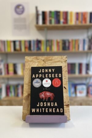 A copy of 'Jonny Appleseed' sits on a stand in front of multiple shelves of other books.