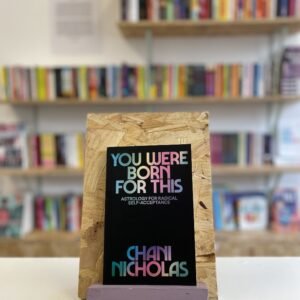 A copy of 'You Were Born For This' sits on a stand in front of multiple shelves of other books.