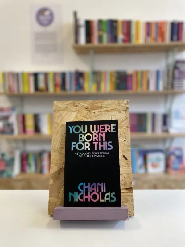 A copy of 'You Were Born For This' sits on a stand in front of multiple shelves of other books.