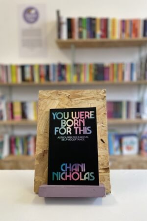 A copy of 'You Were Born For This' sits on a stand in front of multiple shelves of other books.