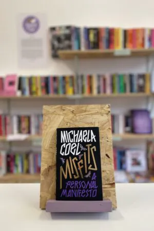 A copy of 'Misfits' sits on a stand in front of multiple shelves of other books.