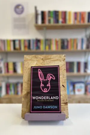 A copy of 'Wonderland' sits on a stand in front of multiple shelves of other books.